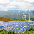 Panouri solare și turbine eoliene în peisaj natural.